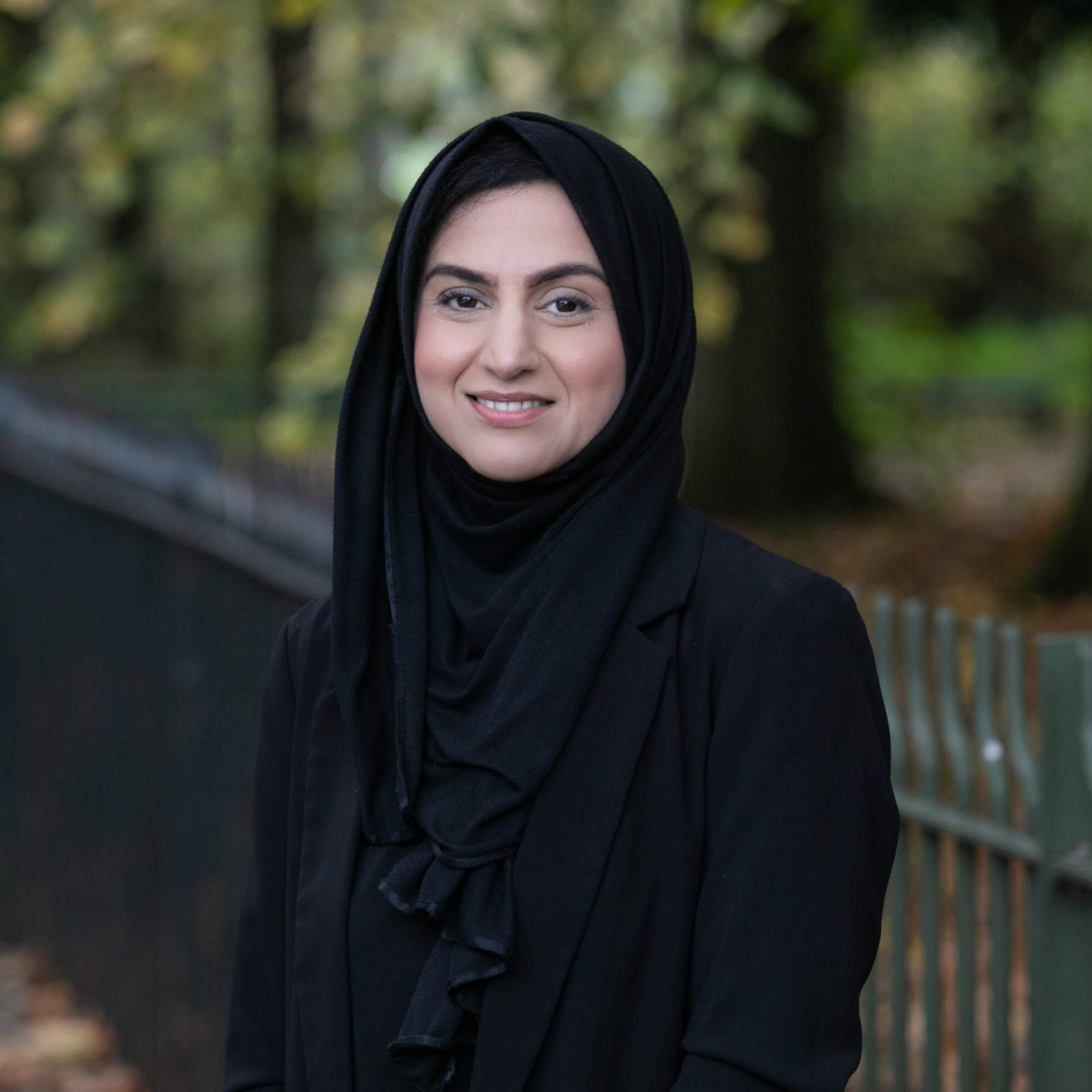 Maryam Saleem, a smartly-dressed solicitor, standing in a vibrant park.