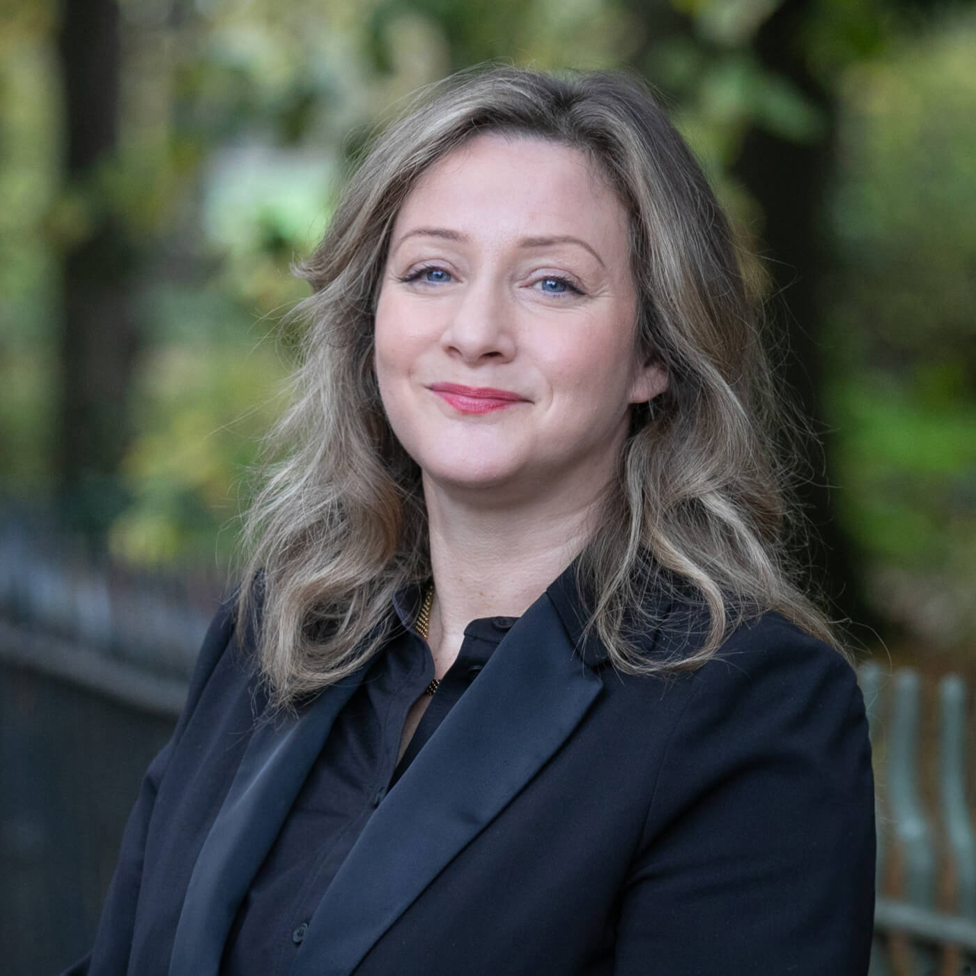 Zoe Taxman, a smartly-dressed solicitor, standing in a vibrant park.